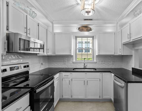 a kitchen with black counter tops and white cabinets