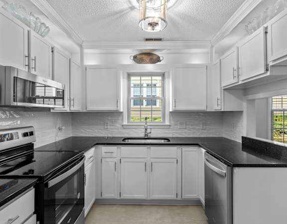 a kitchen with black counter tops and white cabinets