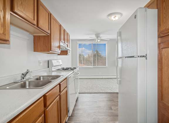 a kitchen with wood cabinets and white appliances and a window