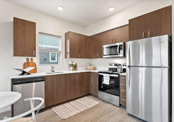 A modern kitchen with a refrigerator, microwave, oven, and sink.