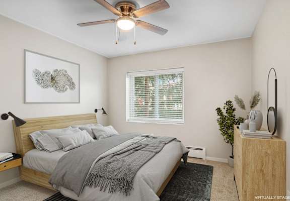 A bedroom with a bed, a ceiling fan, and a nightstand.