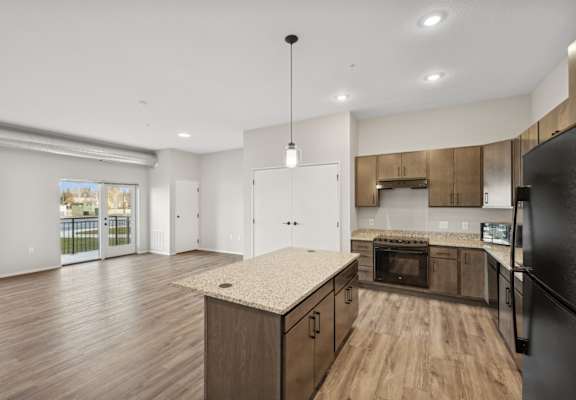 A kitchen with wooden floors and a black refrigerator.