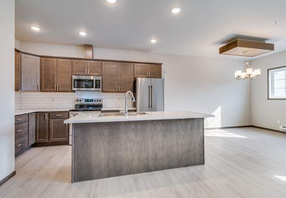 a kitchen with a large center island with a sink and a chrome faucet
