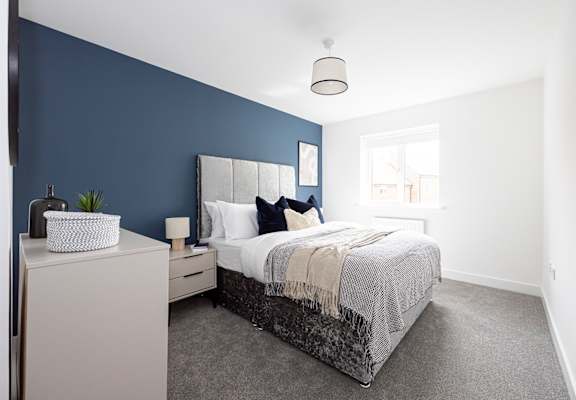 a blue and white bedroom with a bed and a blue accent wall