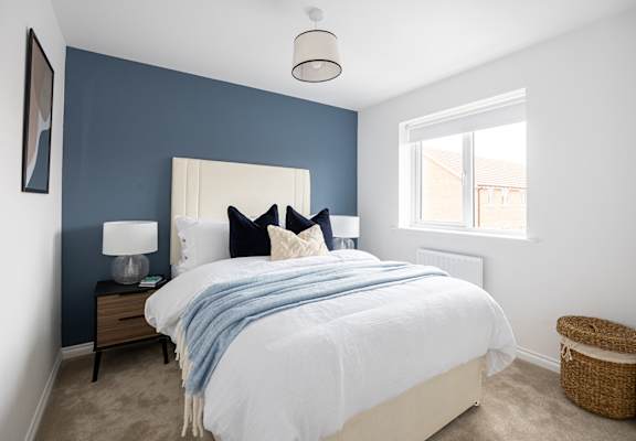 a bedroom with a bed and a blue wall and a window