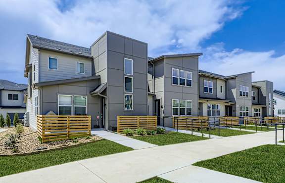 A modern house with a grey facade and a wooden fence in front.