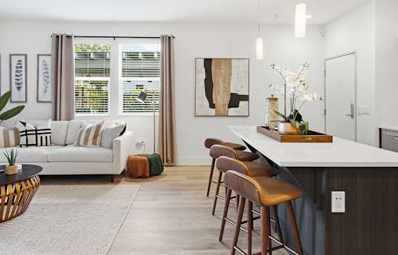 A modern kitchen with a bar stool and a white sofa.