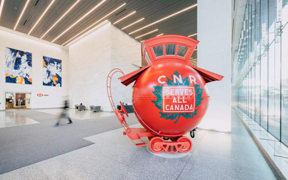 A red CNCR train is in a white room.