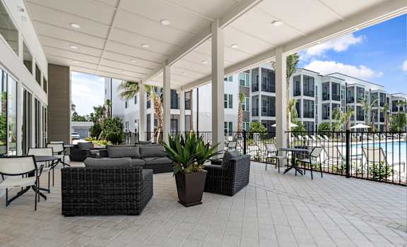 a large patio with furniture and a pool in front of an apartment building at Mira at Palmer Ranch in Sarasota, FL