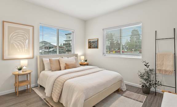 A bedroom with a large bed, a wooden nightstand, and a framed picture on the wall.