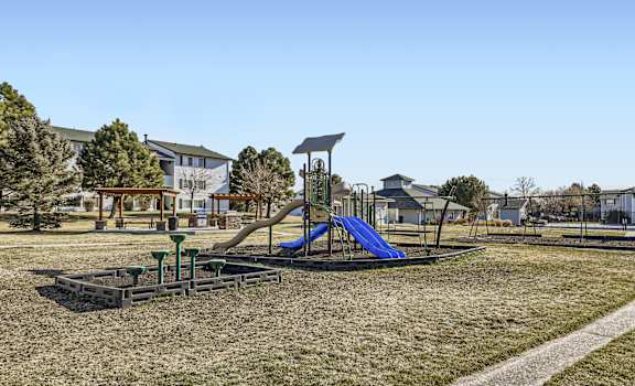 A playground with a blue slide and a green climbing frame.