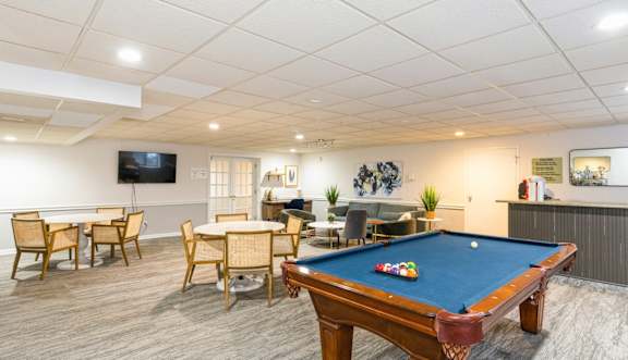 Room with a pool table and many chairs.