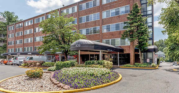 a large brick building with a black awning and a circular garden in front of it