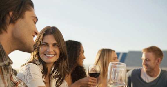 a group of people sitting around a table drinking wine and eating