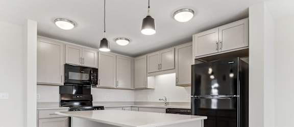 A kitchen with a white island and black appliances.