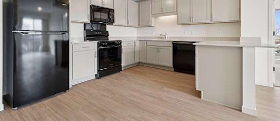 A kitchen with a black refrigerator and white cabinets.