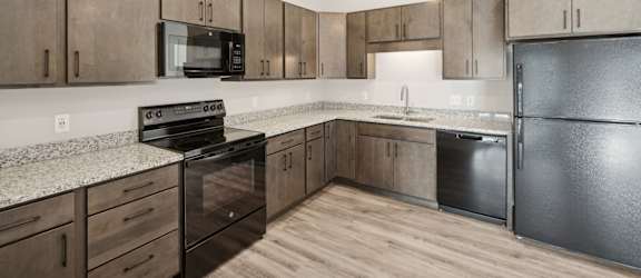 A kitchen with black appliances and wooden cabinets.