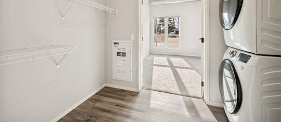 A laundry room with a washer and dryer on the right and a small closet with shelves on the left.