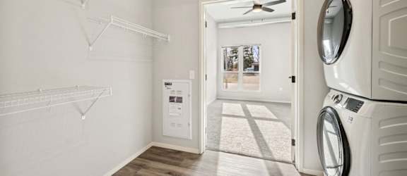A laundry room with a washer and dryer on the right and a small closet with shelves on the left.