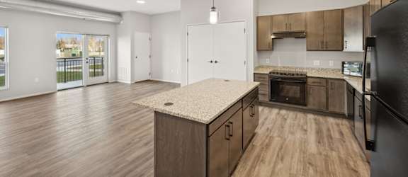 A kitchen with wooden floors and a black refrigerator.