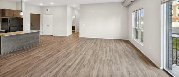 A spacious room with wooden flooring and white walls.