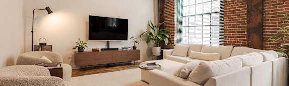 A living room with high ceilings and a mix of white and exposed brick walls