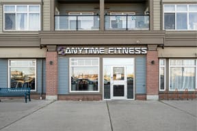 any time fitness building with windows and a bench