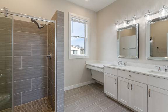 a bathroom with a shower and two sinks and a mirror