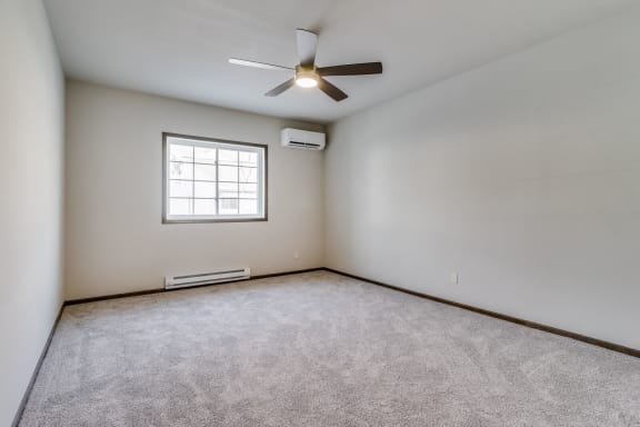 an empty room with a ceiling fan and a window