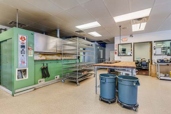 A green and white kitchen with a table and two blue bins.