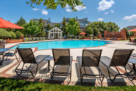 A pool surrounded by lawn chairs and umbrellas.