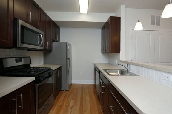 Kitchen with hardwood floors, stainless steel appliances, and dark wooden cabinets