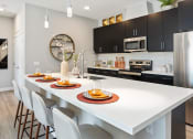 Thumbnail 3 of 9 - a kitchen with a large white island with four plates on it at The Hendry, Henderson, NV, 89074