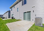 Thumbnail 10 of 11 - A building with a grey siding and a grey air conditioning unit in front.