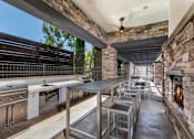 Thumbnail 45 of 62 - Outdoor grill and seating near fireplace at The Grove Apartments, Ontario, 91761