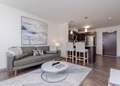 Thumbnail 8 of 9 - Living room area of an apartment, furnished with a sofa, rug, vinyl flooring, and high ceiling.