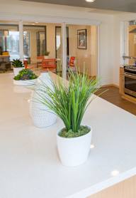 A kitchen with a white counter top and a stainless steel refrigerator.