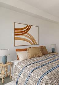 A bedroom with a bed, a lamp, a painting, and a wardrobe.