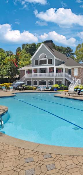 a large swimming pool with a house in the background