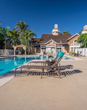 Two chairs are placed on a patio by a pool.