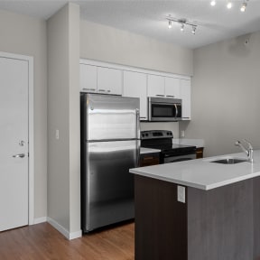 an empty kitchen with stainless steel appliances and a white counter top