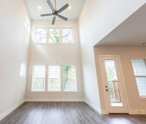 an empty living room with a ceiling fan and windows