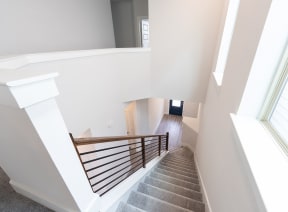a view from the top of a staircase in a house with white walls and stairs