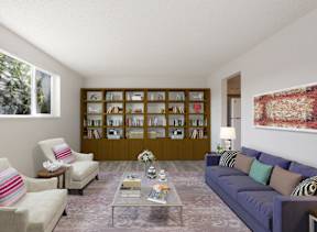 A living room with a white couch, a chair, a coffee table, and a painting on the wall.