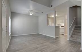 A spacious room with wooden flooring and a staircase leading to another room.