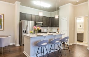a kitchen with a large island with three stools at The Roseberry Apartments in Columbia, SC