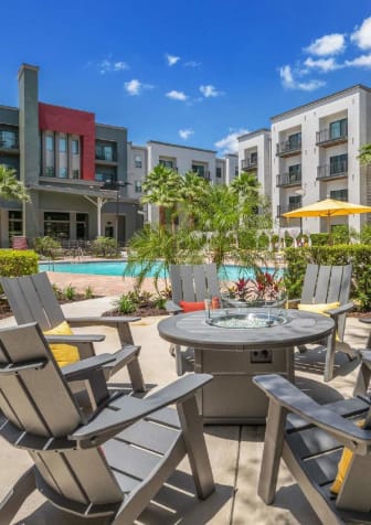 a patio with chairs and a table in front of an apartment building