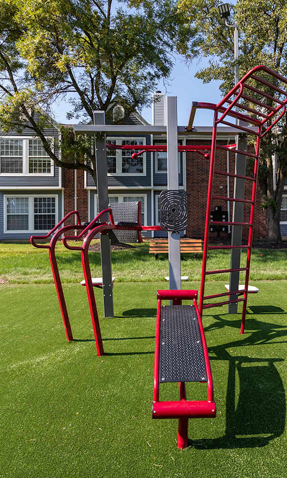 A playground with a red slide and a green lawn.