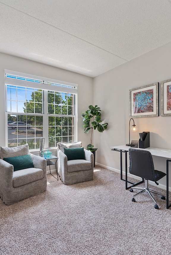 A room with a desk, chairs, and a window.