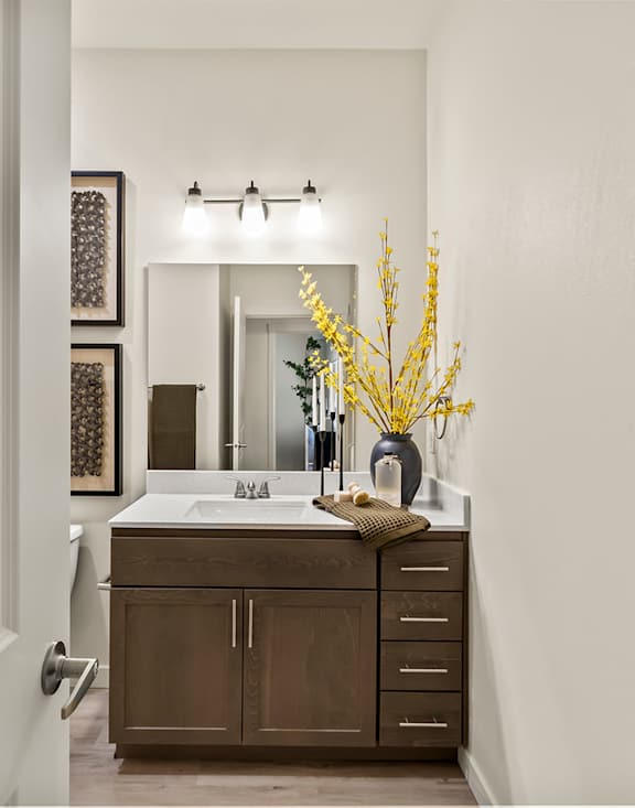 A bathroom with a brown vanity and a white sink.